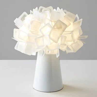 Nordic style decorative table lamp with metal base in a choice of six colours on a wooden bedside table.