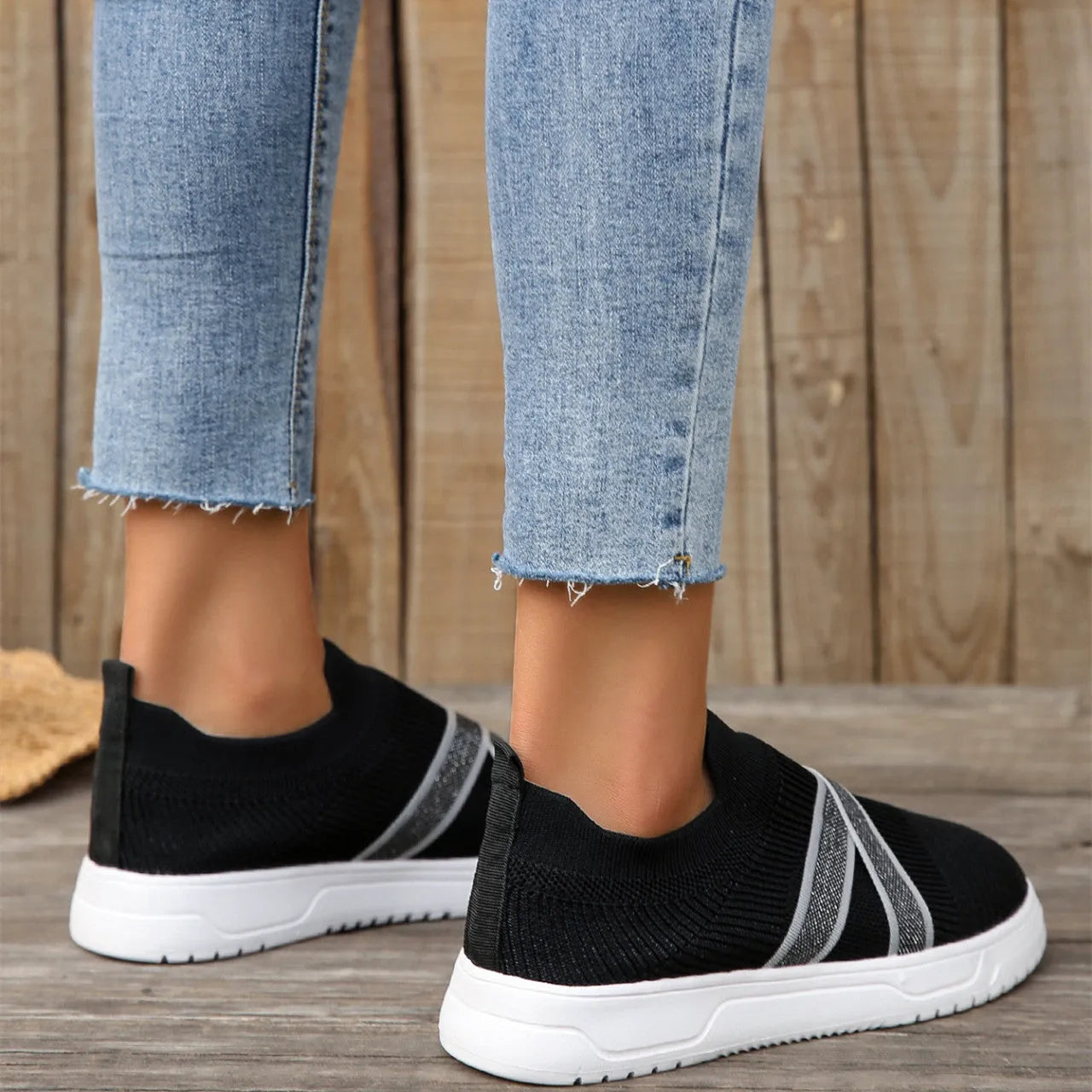 Black women's casual trainers with flyknit mesh upper, flat rubber sole, round toe, and a tassel detail.