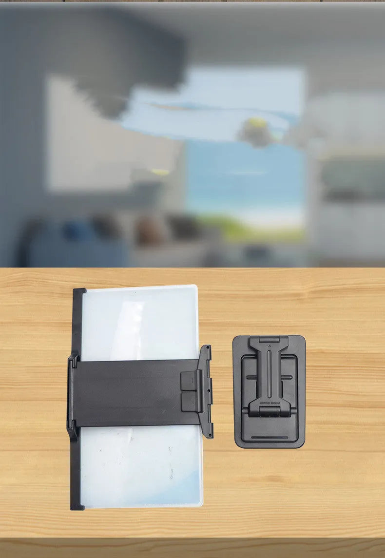 Black folding mobile phone screen magnifier with detachable holder on a desktop.