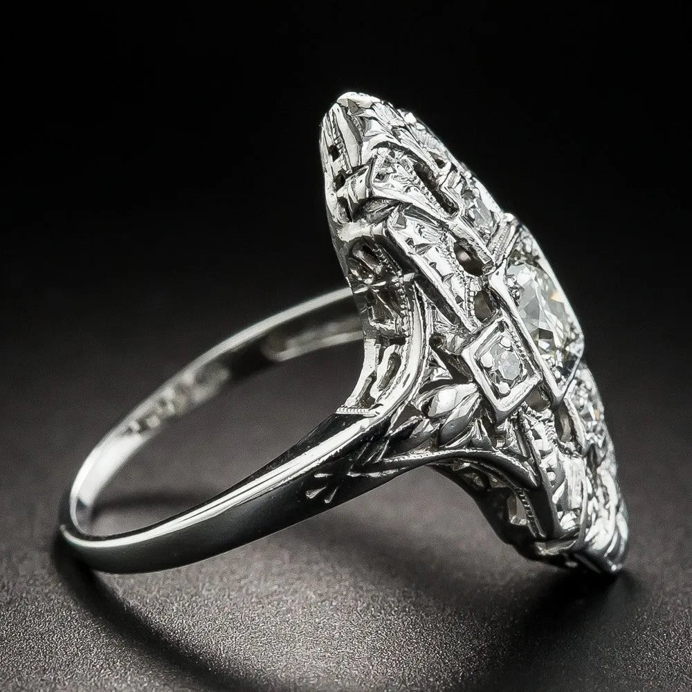 Geometric hollow-out silver ring with diamond studs on a finger.