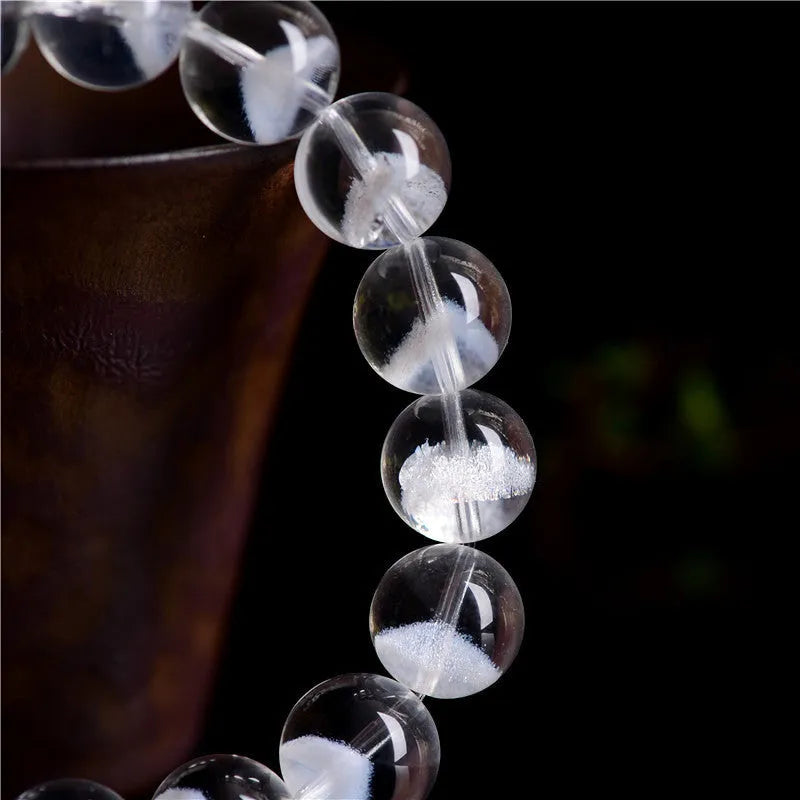 Women's white crystal bracelet with a ghost pyramid charm and Ruyi symbol, showing round beads.