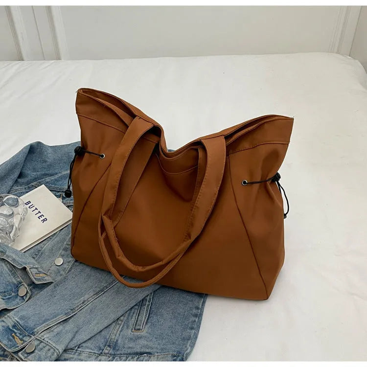 A foldable Oxford cloth commuter shoulder tote bag shown in one of five colours: black, brown, dark gray, light gray, or purple.