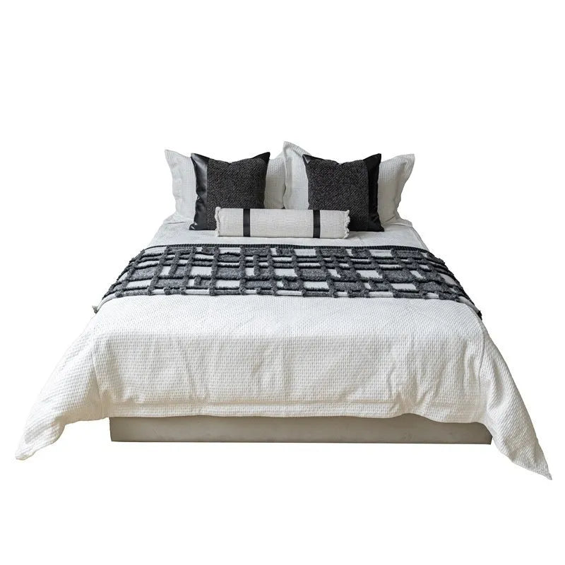 Grey and white plaid bed runner blanket and matching pillow on a double bed.