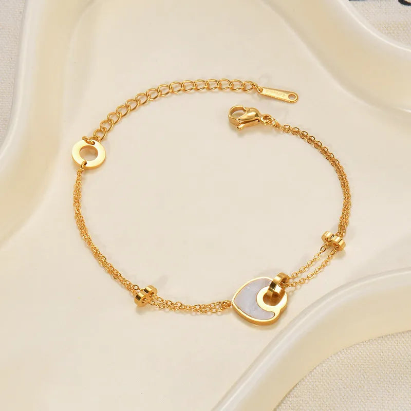 Close-up of a women's stainless steel bracelet featuring a double-layer heart charm with resin details.