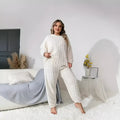 Creamy white women's long sleeve crew neck top and trouser set on a hanger.
