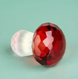 A set of colourful crystal mushroom decorations in transparent, green, red, and yellow on a white surface.