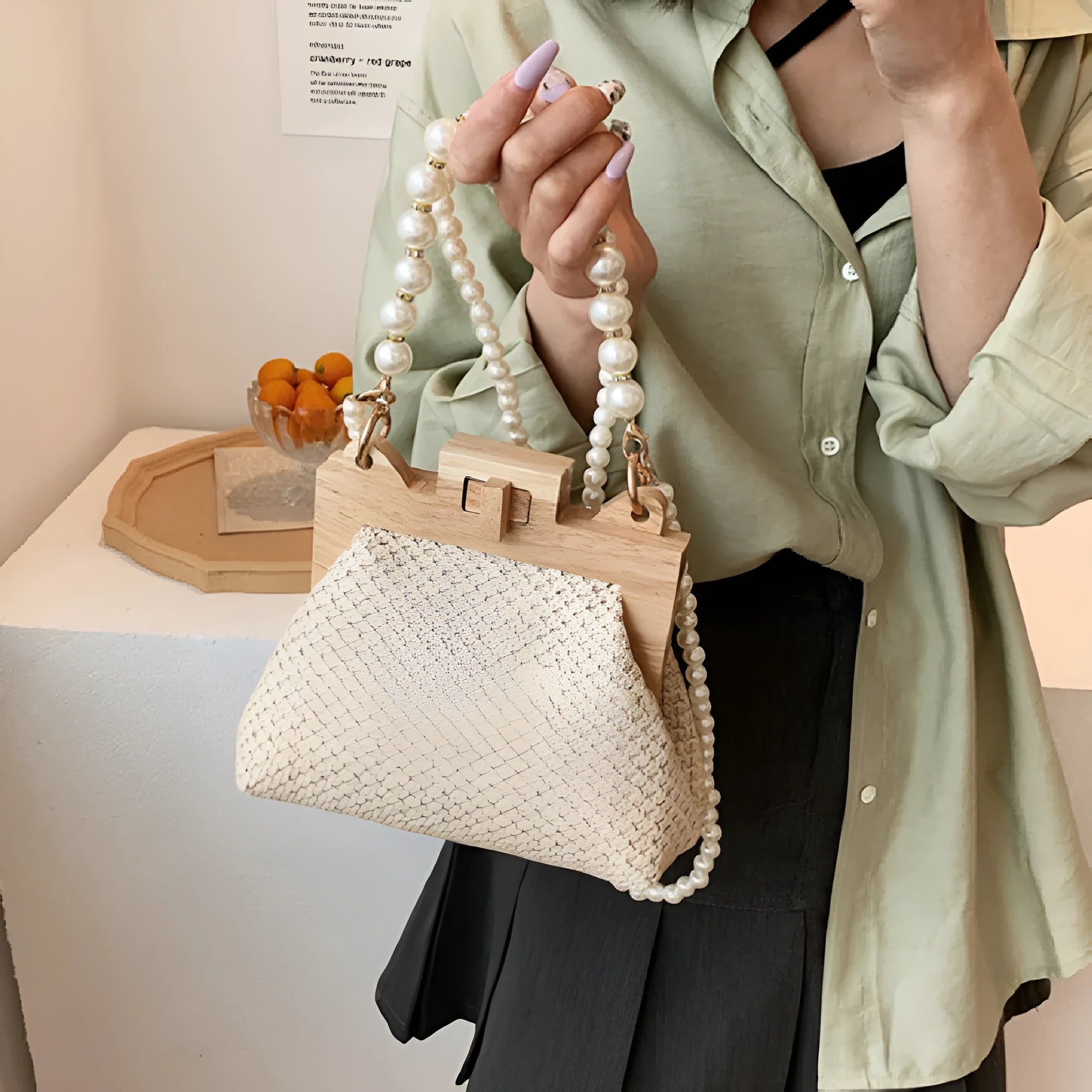 Women's woven straw shoulder bag with pearl chain detailing in horizontal square shape showing internal compartments