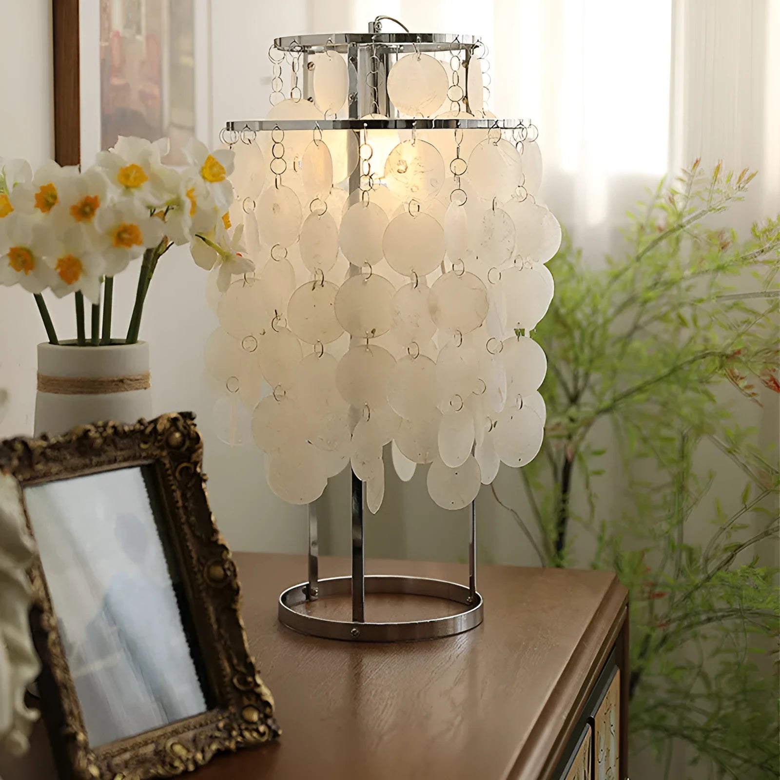Modern bedside table lamp with a decorative white shell-shaped shade on a metallic chrome or gold base.