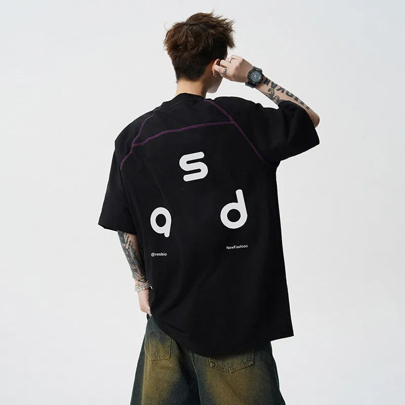 Man wearing a black loose-fit cotton t-shirt with a white letter print on the front.