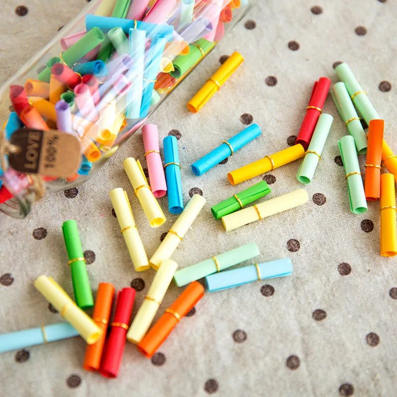 Multi-coloured mini paper scrolls in various sizes with metal eyelets for hanging.