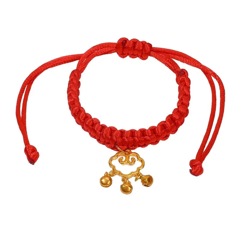 Adjustable hand-woven red rope pet collar with alloy lucky charm on wooden surface
