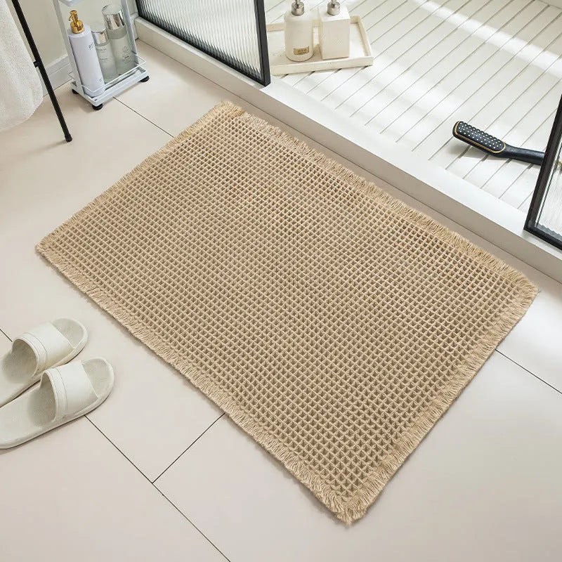 A square, checkered-pattern absorbent bathroom floor mat with a non-slip backing, shown in a neutral colour.