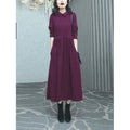 Purplish red long sleeve dress for women on a hanger, showing long skirt and extra long sleeves.