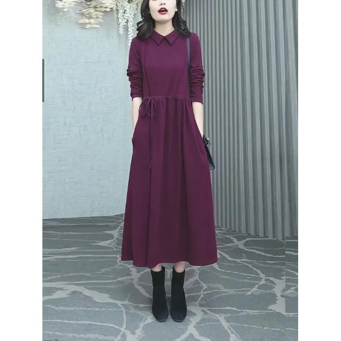 Purplish red long sleeve dress for women on a hanger, showing long skirt and extra long sleeves.