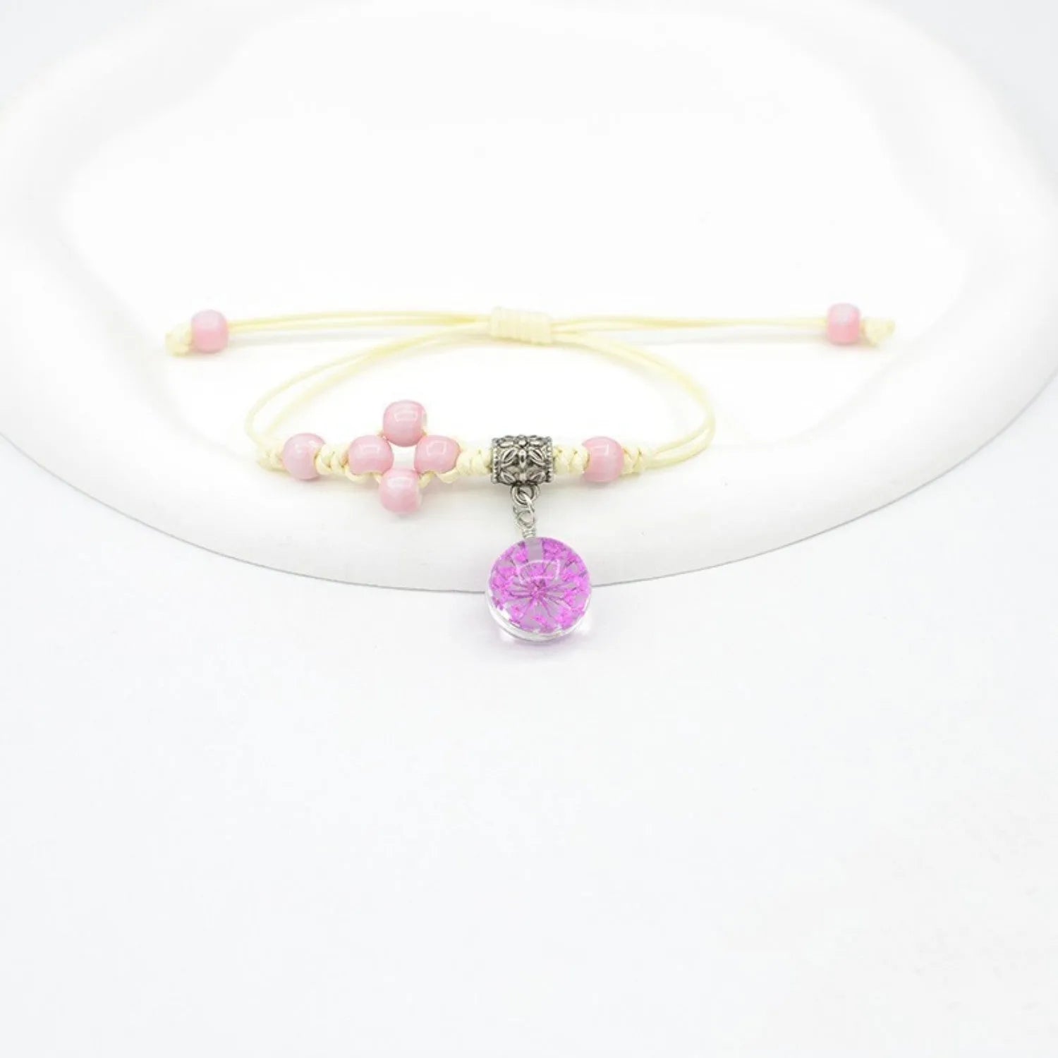 Close-up of a hand-woven glass bracelet with large beads containing real dried flowers and a lace design.