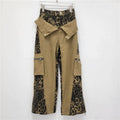 Dark khaki high-waist jeans with a leopard print pattern and tooling-style stitching details on the legs.
