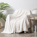 Shu cotton velvet jacquard sofa blanket with plant flower pattern in solid colour on a grey sofa.