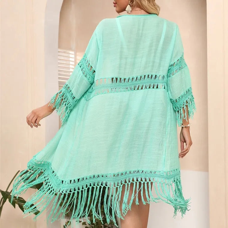 Yellow hand-crocheted women's cardigan with tassels, laid flat as a beach cover-up.