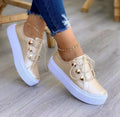 Women's white lace-up flats sneakers with decorative silver rivets on the sides.