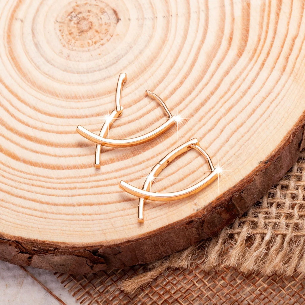 Rose gold plated cross-shaped drop earrings on a copper base.