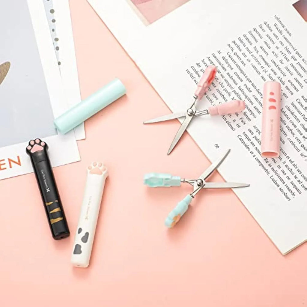 Small stainless steel folding scissors with cat paw handles shown in pink, blue, black, and white.