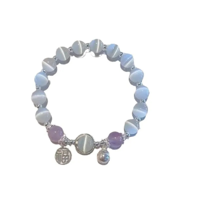 Close-up of a drop-shaped glass butterfly bracelet with round coloured beads on a wrist.