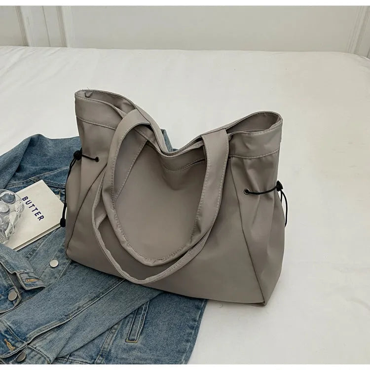 A foldable Oxford cloth commuter shoulder tote bag shown in one of five colours: black, brown, dark gray, light gray, or purple.