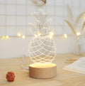 Cartoon pineapple shaped bedside table lamp with wooden base and acrylic body on a white surface.