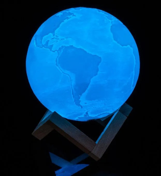 3D printed white moon lamp on a wooden stand, showing detailed lunar surface texture.