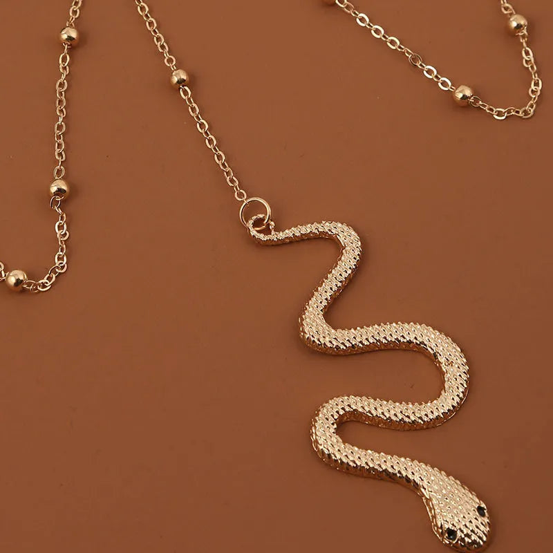 Gold metal beaded thigh chain with large snake pendant and artificial gem inlay, worn on a woman's leg