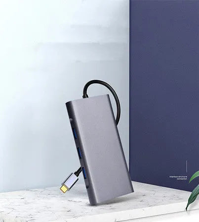 Silver 10-in-1 USB-C docking hub for MacBook with multiple ports including HDMI, USB, and SD card slots.