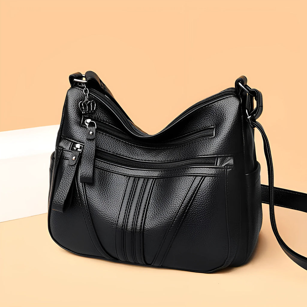 Genuine leather horizontal square messenger bag in black with contrast stitching and a front slit pocket.