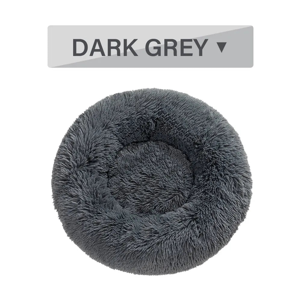 Fluffy donut-shaped dog bed in long plush material, shown in a light grey colour.