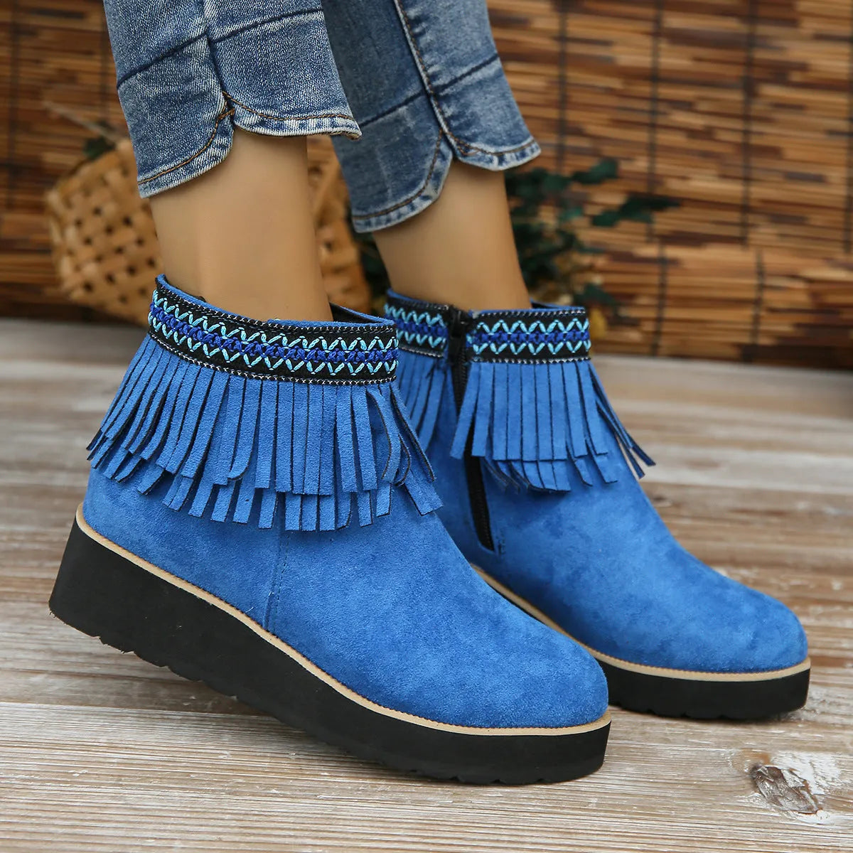 Women's suede ankle boots with a wedge heel, side zipper, tassel detail, and thick rubber sole.