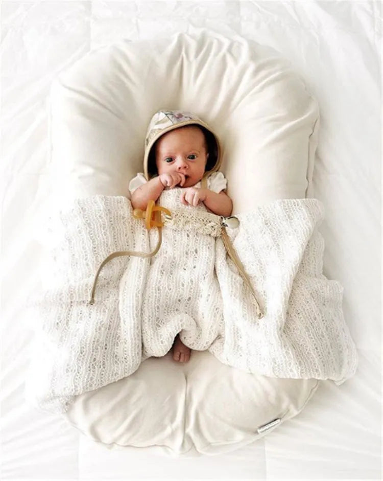 Beige portable baby nest crib for newborns measuring 75cm by 45cm on a neutral background.