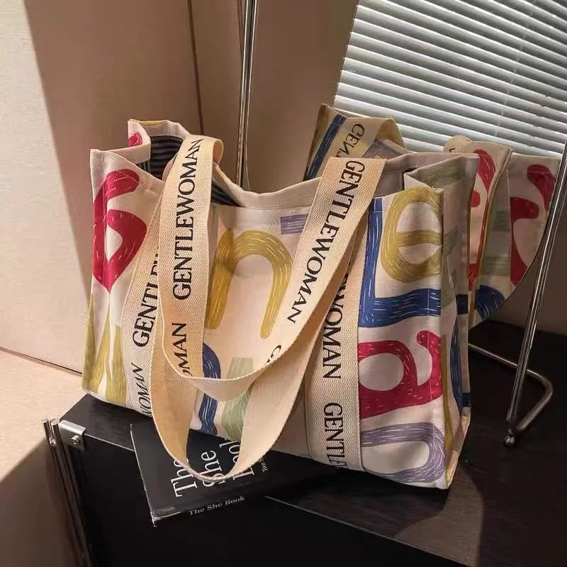 Large canvas tote bag with printed design, featuring two fabric handles, shown in available colour style options.