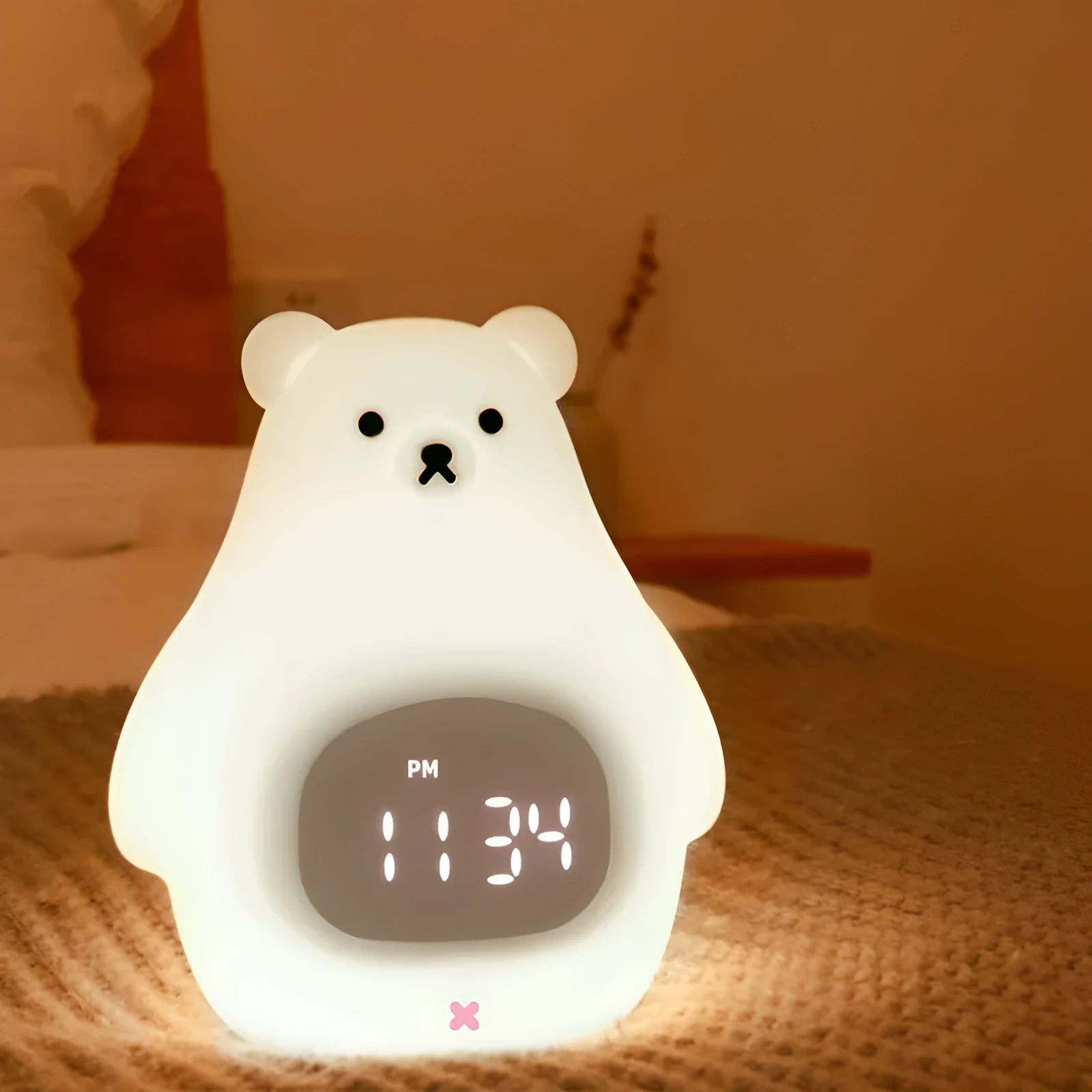 White silicone bear-shaped night light with a remote control on a wooden surface.