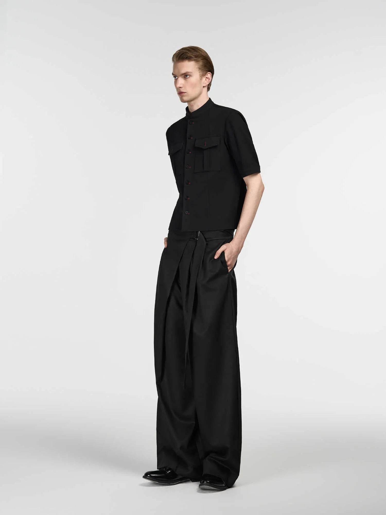 Black straight-leg Tencel cotton trousers with a single pleat and adjustable waistband on a hanger.