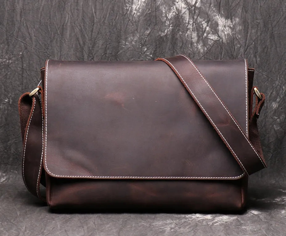 Men's vintage brown cowhide medium messenger bag showing front flap and long shoulder strap.