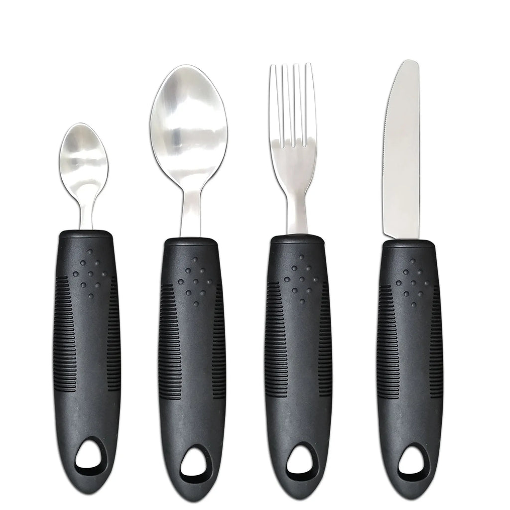 Stainless steel adaptive knife, fork, and spoon set with black rubber handles on a table.