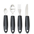 Stainless steel adaptive knife, fork, and spoon set with black rubber handles on a table.