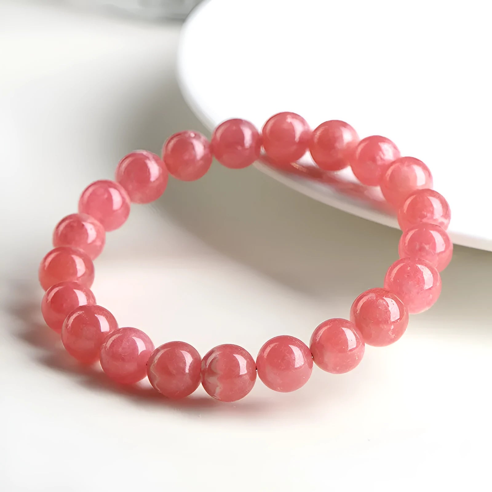 Women's red crystal bracelet with a geometric longevity lock clasp on a wrist.