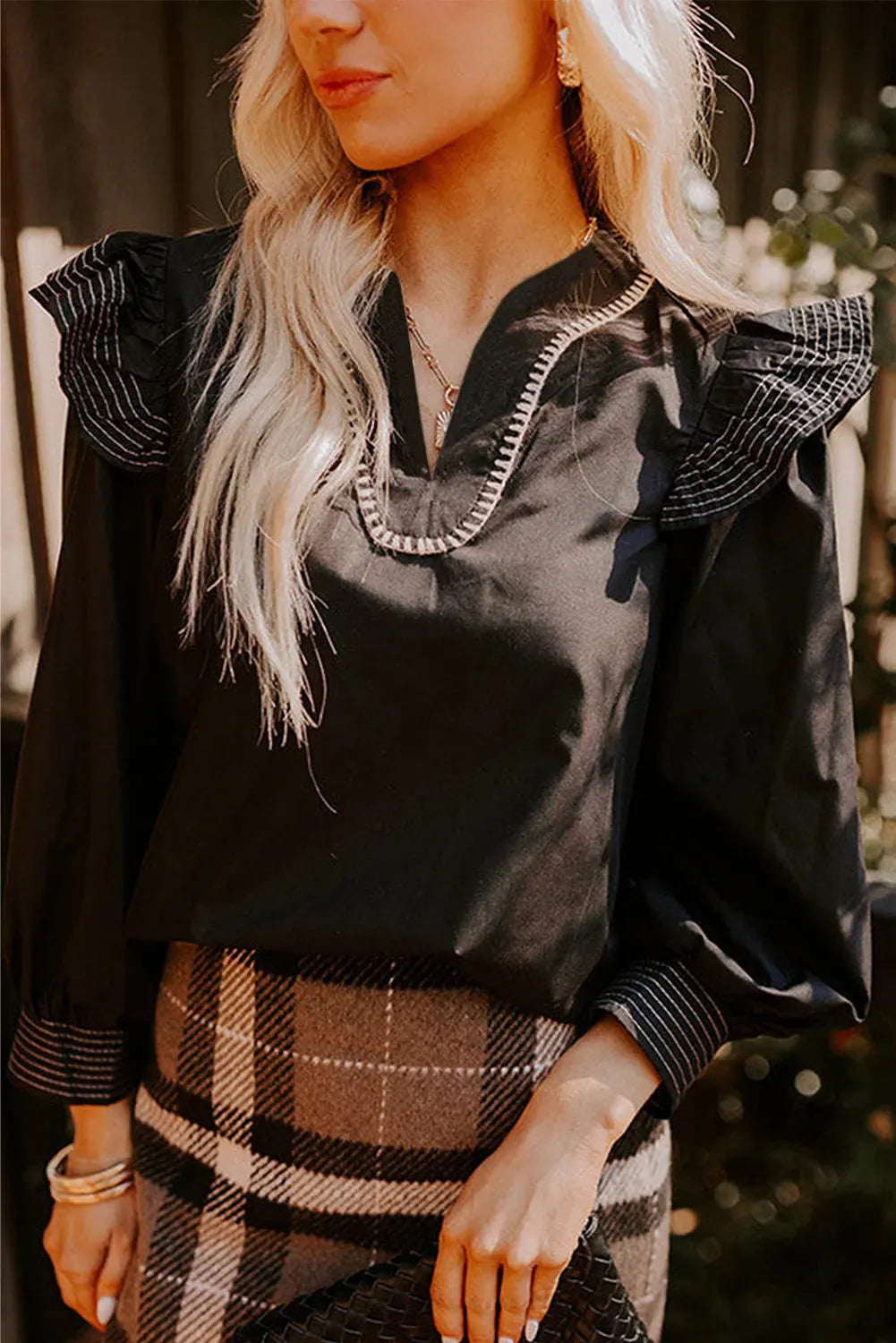 Black women's long sleeve blouse with V-neck, contrast stitching, and ruffle sleeve details.