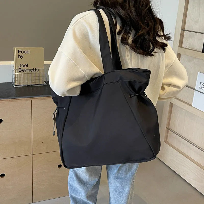 A foldable Oxford cloth commuter shoulder tote bag shown in one of five colours: black, brown, dark gray, light gray, or purple.