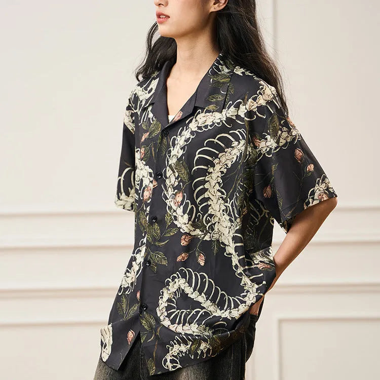 Man wearing a loose fit Cuban collar shirt with a printed snake bone and floral pattern in a summer setting.