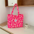 Large pink women's canvas shoulder bag with a textured three-dimensional front pocket.