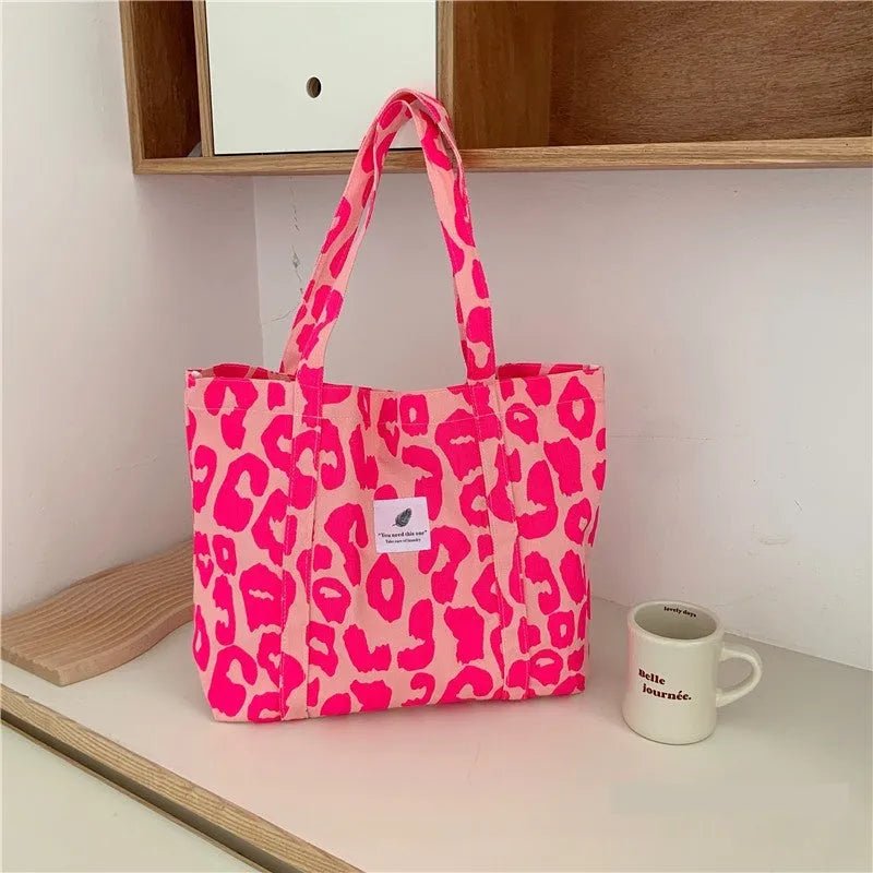 Large pink women's canvas shoulder bag with a textured three-dimensional front pocket.