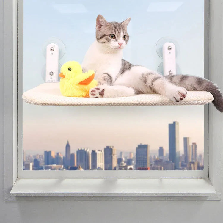 Grey plush cat window hammock with stainless steel suction cups mounted on a glass pane