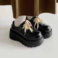 Women's matte black retro platform shoes with chunky rubber sole and lace-up buckle.