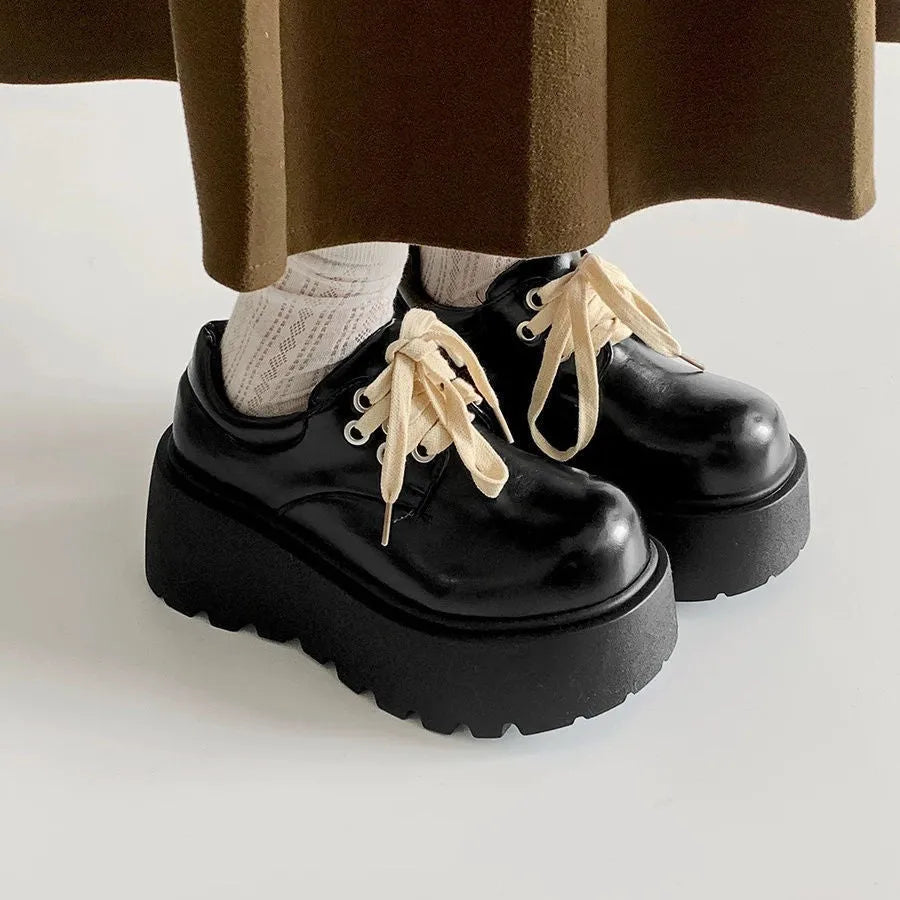 Women's matte black retro platform shoes with chunky rubber sole and lace-up buckle.